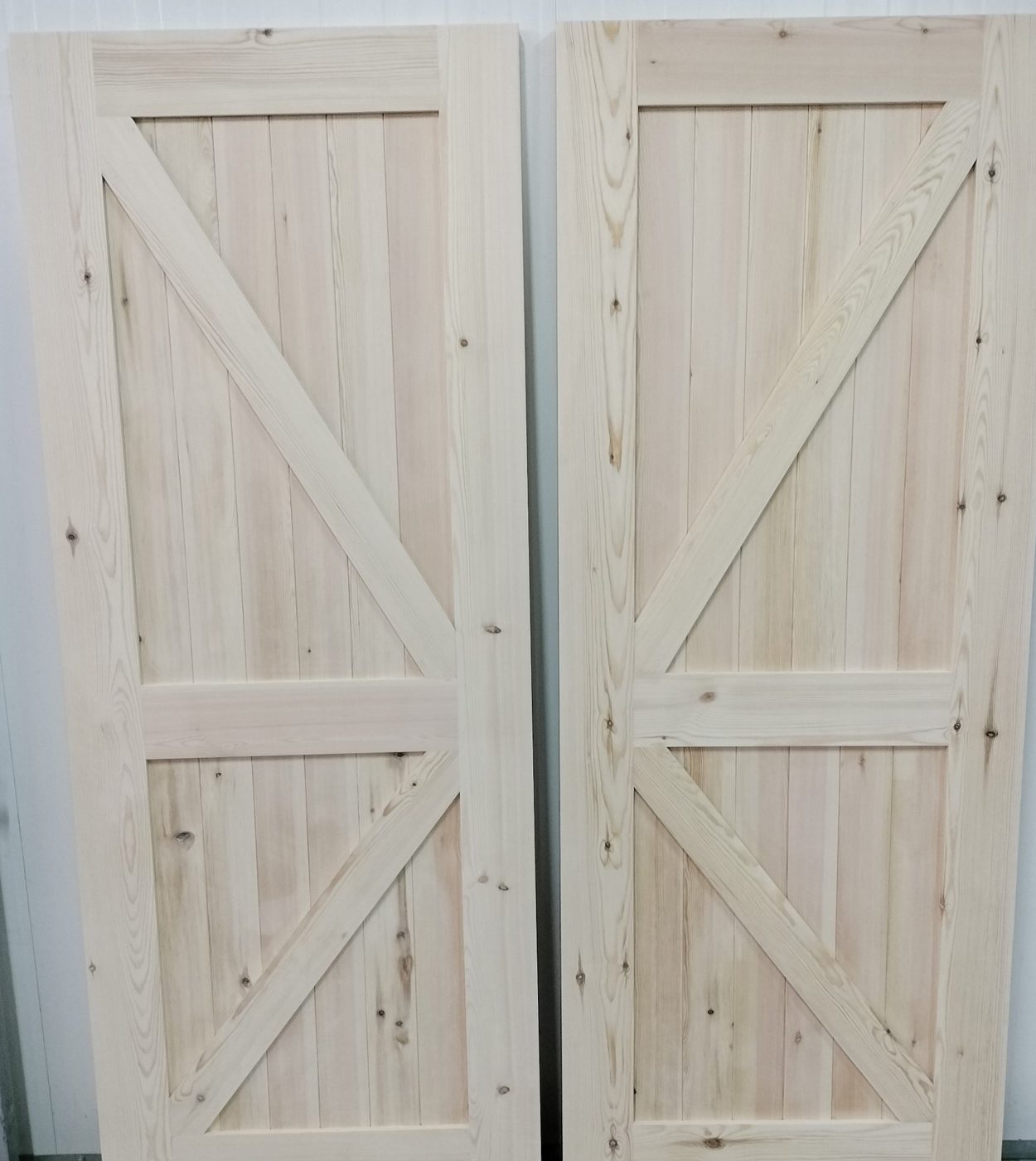 Duas portas estilo celeiro em madeira, com travessas em diagonal